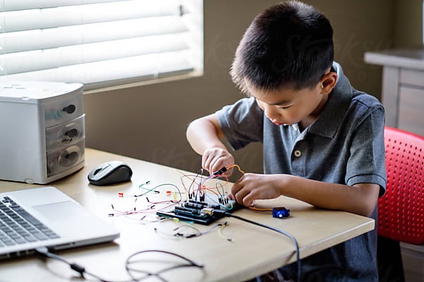 A focused student building a hands-on electronics project at home